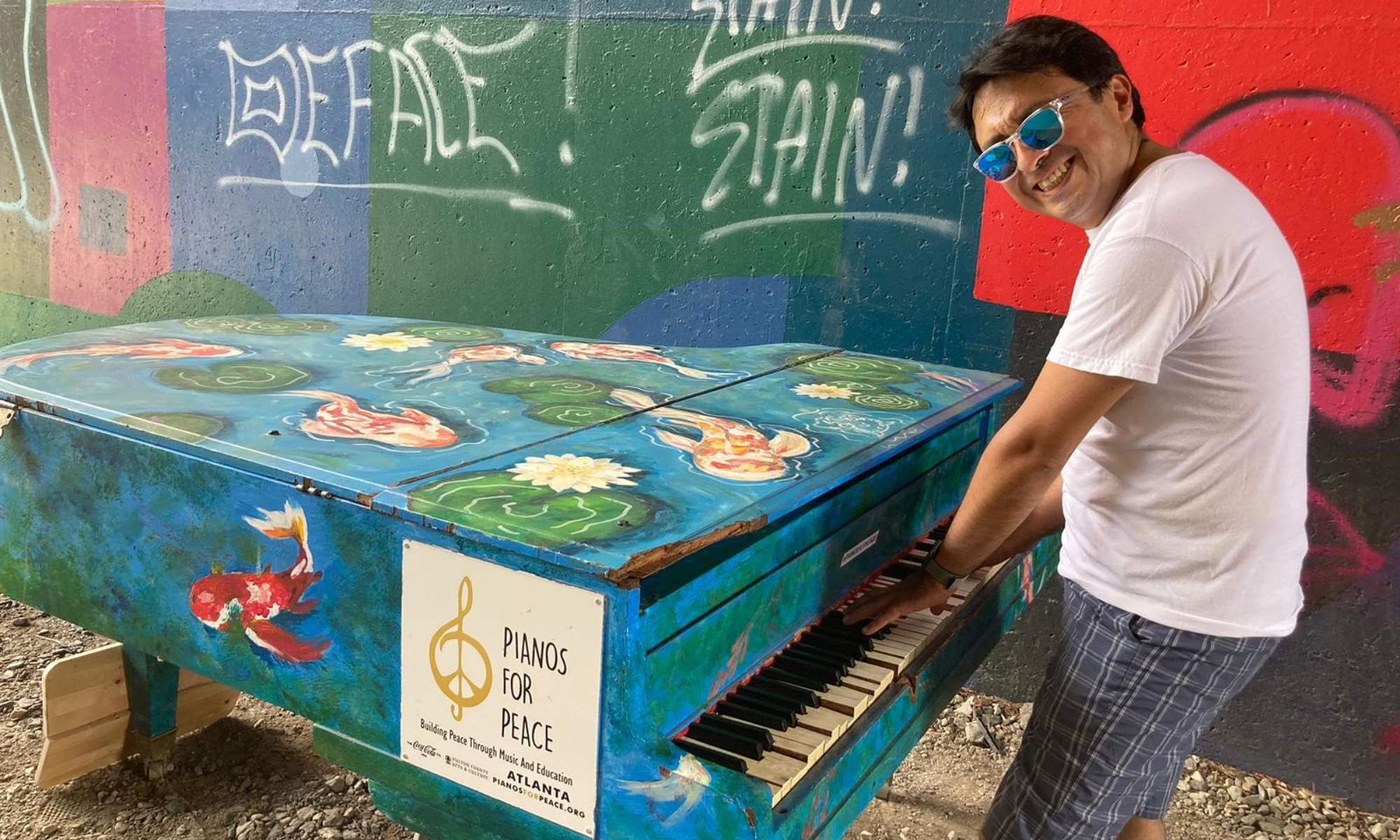 Boris Cepeda mit Sonnenbrille am bunten Klavier in Atlanta, draußen