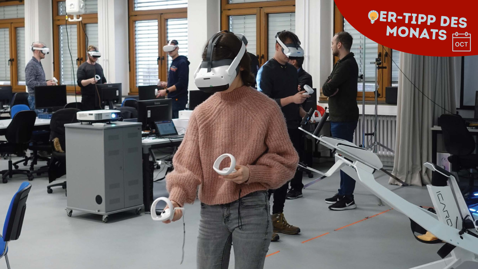 Studentin mit VR-Headset und zwei Controllern in einem Seminarraum