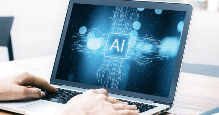 Zwei Hände am Laptop, auf dem Bildschirm steht "AI"