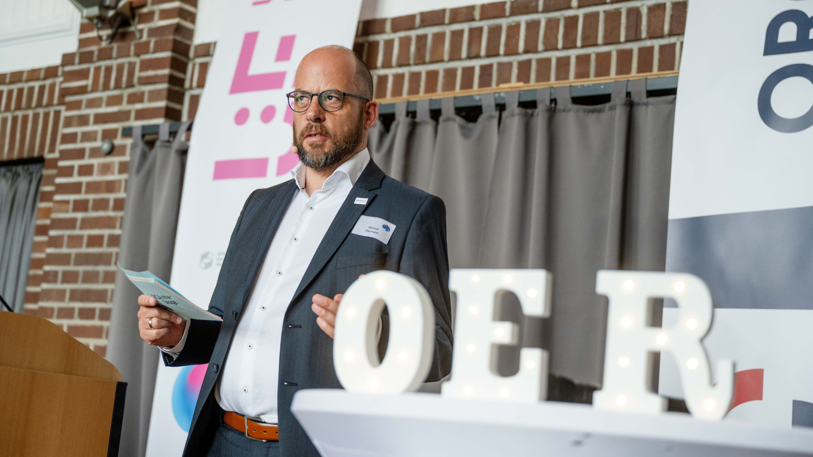 Markus Deimann auf dem Podium, neben ihm die Buchstaben O, E und R