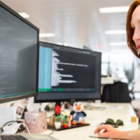 Frau mit rötlichen Haaren am PC, die Monitore zeigen Ordnerstrukturen an