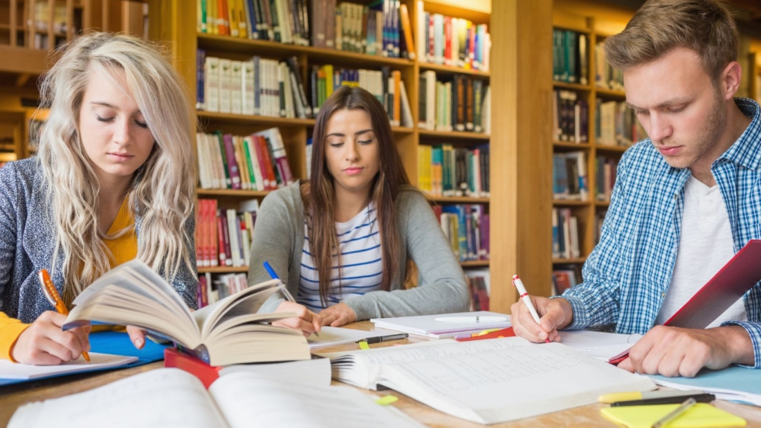 Studierende sitzen schreibend in der Bibliothek