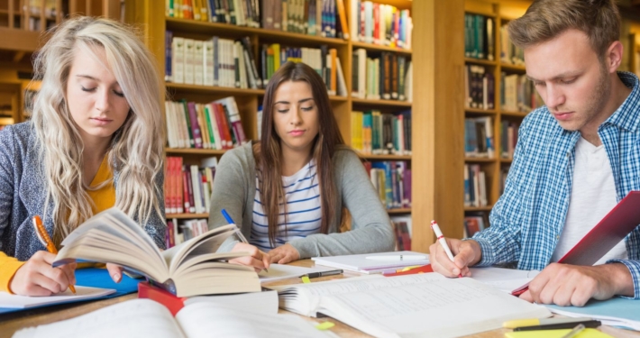 Studierende sitzen schreibend in der Bibliothek