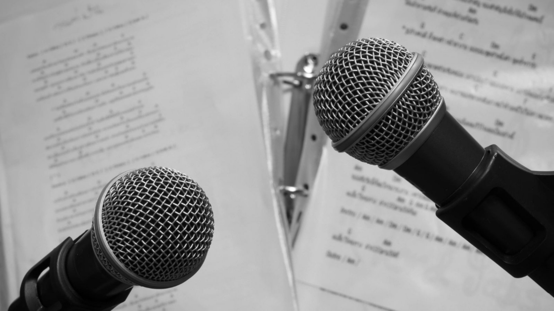 Zwei Mikrofone, dahinter Notenblätter
