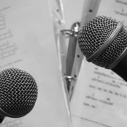 Zwei Mikrofone, dahinter Notenblätter