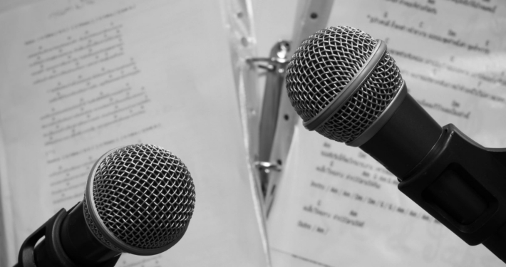 Zwei Mikrofone, dahinter Notenblätter