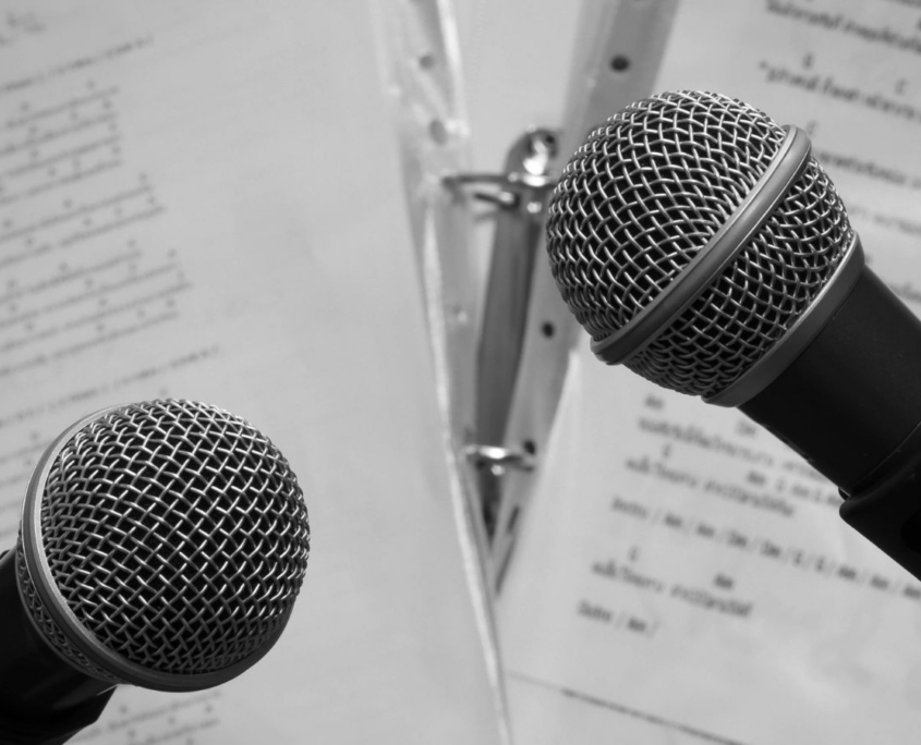 Zwei Mikrofone, dahinter Notenblätter