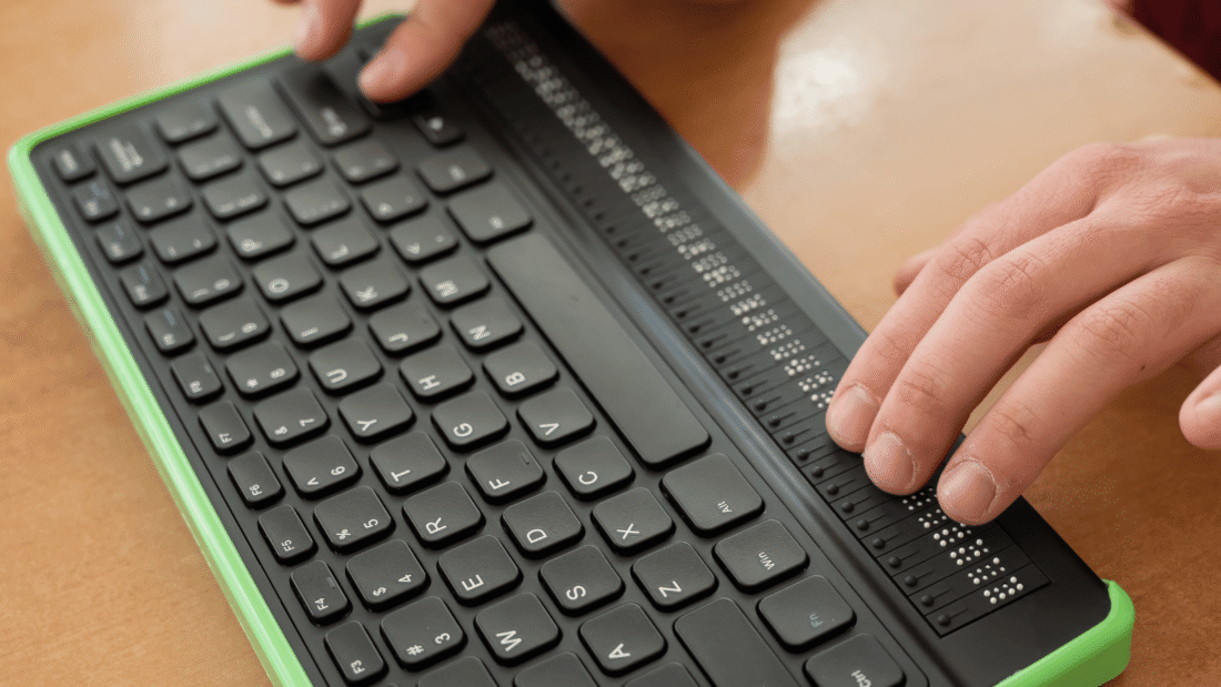 Zwei Hände tippen auf einer Computer-Braille-Tastatur.