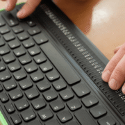 Zwei Hände tippen auf einer Computer-Braille-Tastatur.
