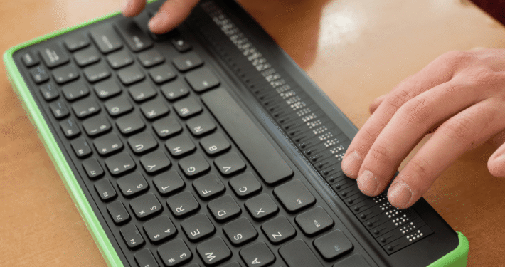 Zwei Hände tippen auf einer Computer-Braille-Tastatur.